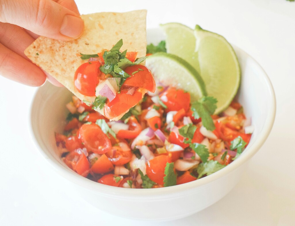White bowl with fresh fermented salsa inside and a wedge of lime.